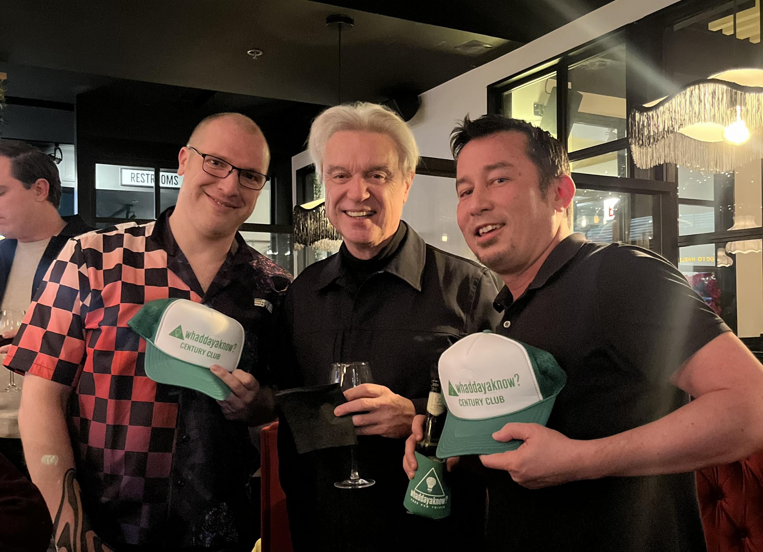 Horizonal photo of Gordon and Dan holding Whaddayaknow? hats with David Byrne