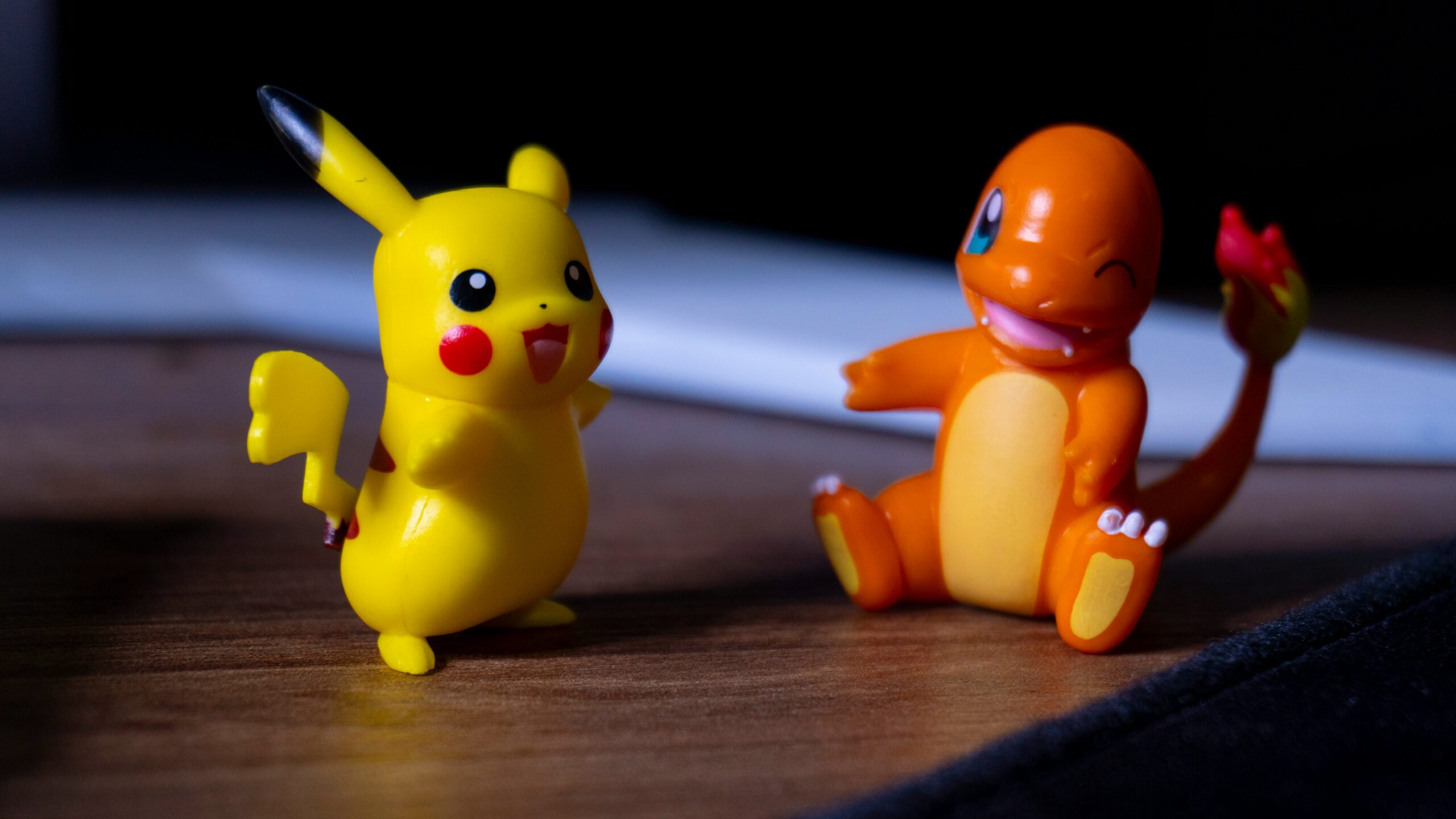 Two Pokémon figurines on a table with shadows cast behind them